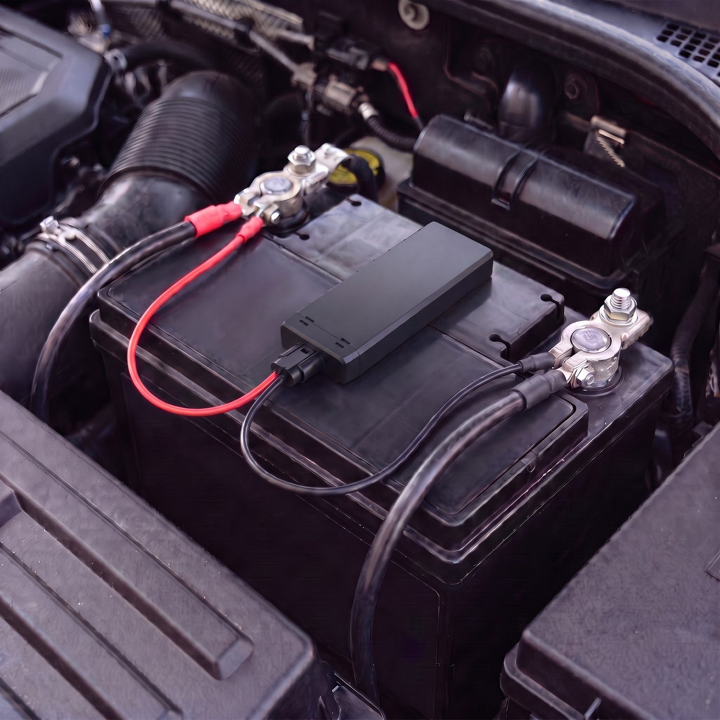 CT-V07 battery-mount tracker fitted on top of a vehicle battery, its red wire on the positive terminal and its black wire on the negative