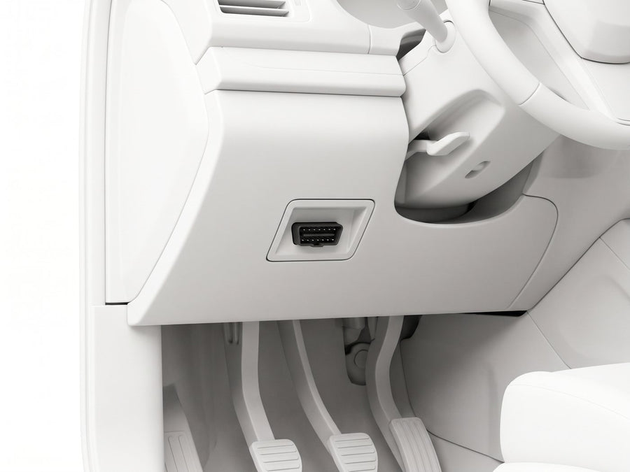 A vehicle’s OBD-II port under the dashboard, near the steering column